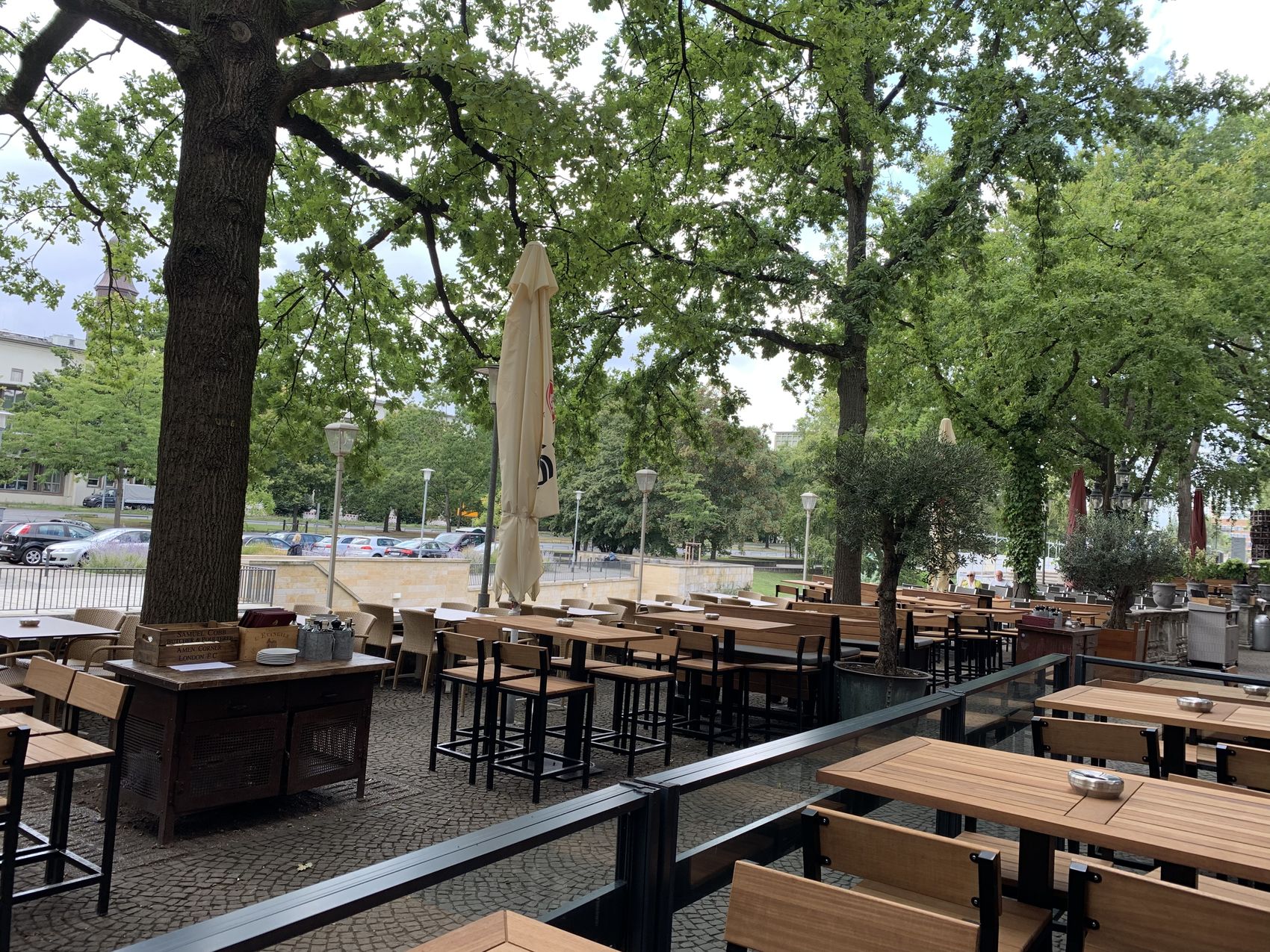 Die Terrasse des A'MURA unter alten Bäumen am Leineufer
